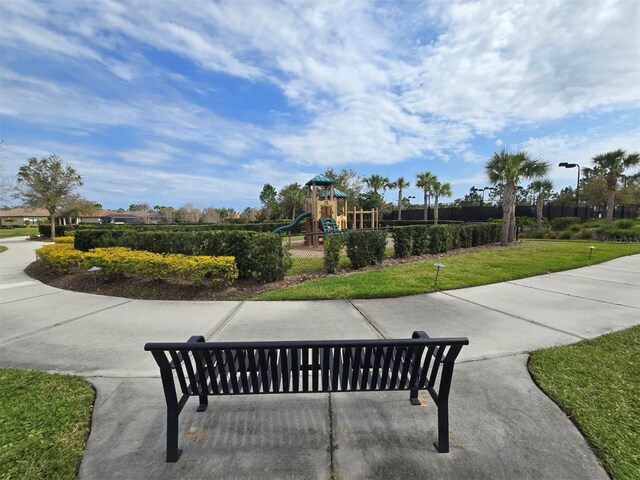 view of home's community featuring fence, playground community, and a lawn