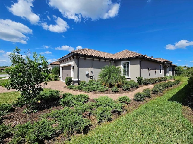 view of side of home with a tiled roof, stucco siding, an attached garage, and decorative driveway