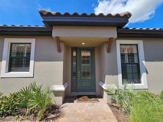 entrance to property featuring stucco siding and a tiled roof