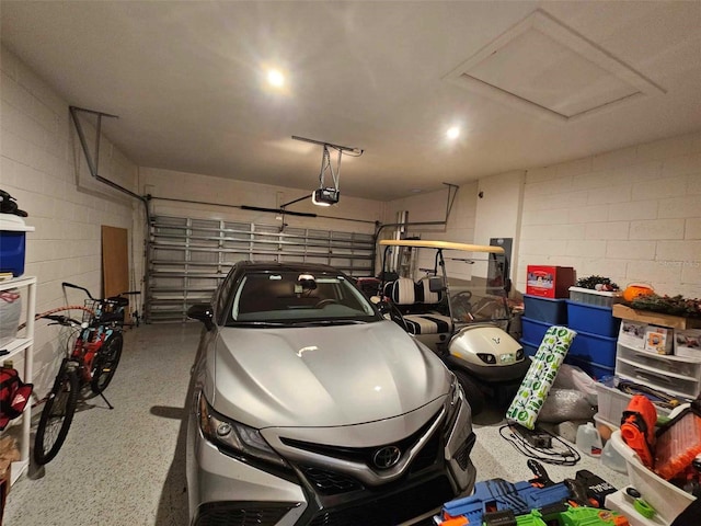 garage featuring a garage door opener and concrete block wall