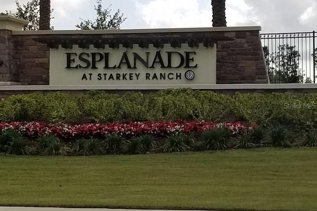 community / neighborhood sign featuring a yard and fence