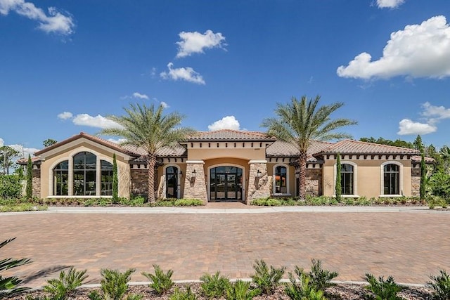 mediterranean / spanish-style house with a tiled roof, stone siding, and stucco siding