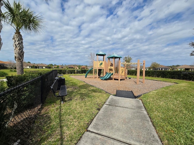 communal playground featuring a yard and fence