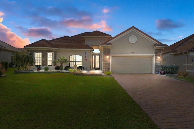 mediterranean / spanish house with a garage and a lawn