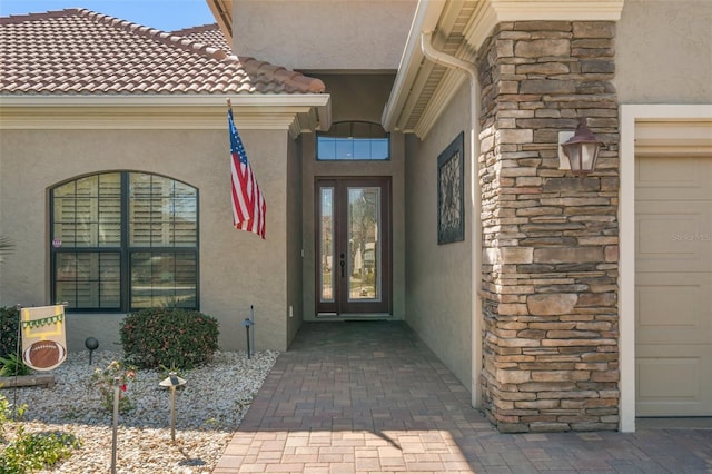 view of exterior entry featuring a garage and french doors