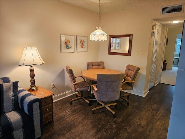 dining space with a textured ceiling and dark hardwood / wood-style flooring