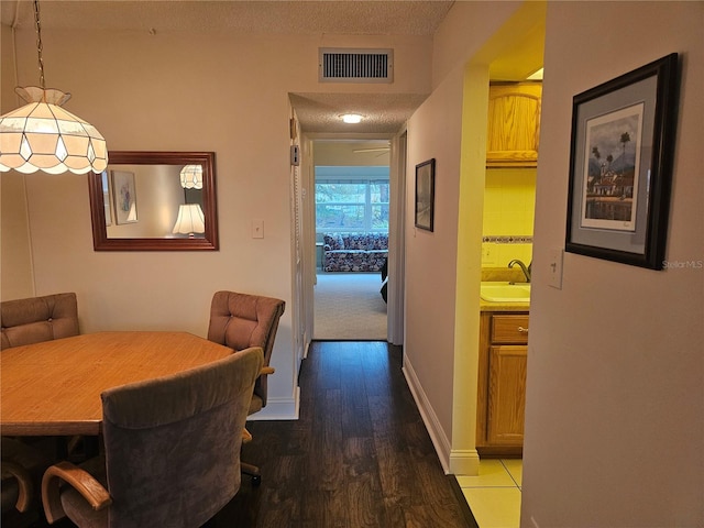 dining area with a textured ceiling, hardwood / wood-style flooring, and sink