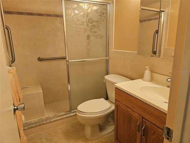 bathroom featuring toilet, a shower with door, vanity, tile walls, and tile flooring