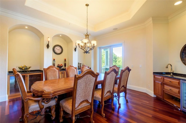 dining area with a raised ceiling, crown molding, a notable chandelier, and dark wood-type flooring