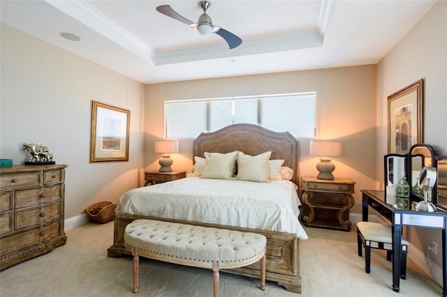 carpeted bedroom with ceiling fan and a tray ceiling