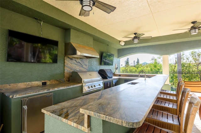 view of patio / terrace with grilling area, an outdoor kitchen, ceiling fan, and an outdoor wet bar