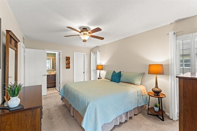 carpeted bedroom featuring ceiling fan, connected bathroom, and a textured ceiling