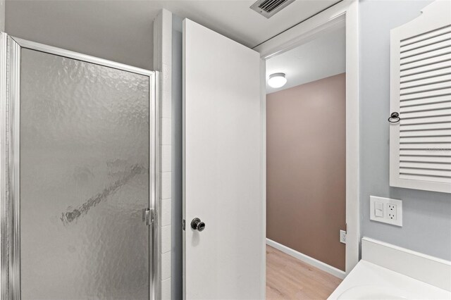 bathroom featuring an enclosed shower and hardwood / wood-style flooring