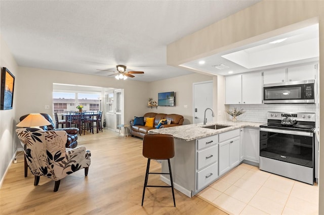 kitchen with white cabinetry, sink, light stone counters, and appliances with stainless steel finishes