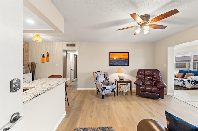 interior space featuring ceiling fan, a textured ceiling, and light hardwood / wood-style flooring