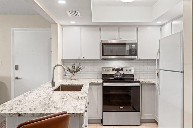 kitchen featuring stainless steel appliances, tasteful backsplash, sink, and white cabinets