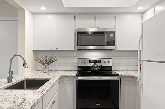 kitchen featuring white cabinetry, range with electric cooktop, and white fridge