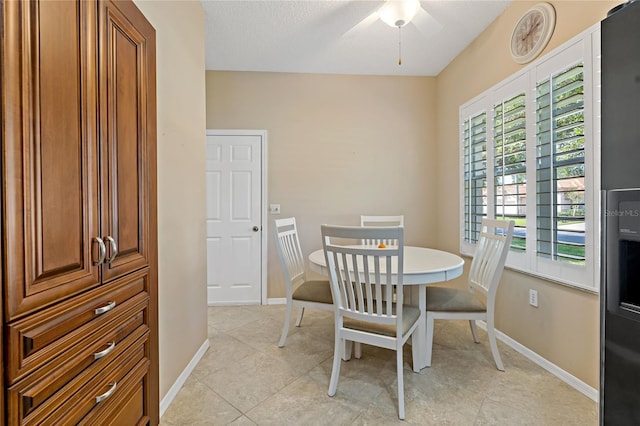 tiled dining room with ceiling fan and a textured ceiling