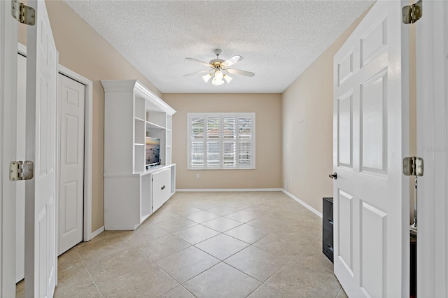 tiled empty room featuring ceiling fan and a textured ceiling