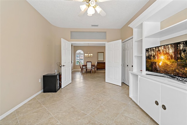 hallway featuring a textured ceiling, light tile floors, and an inviting chandelier