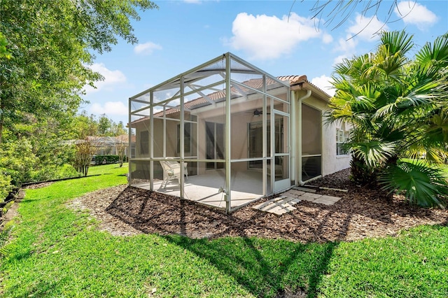 back of house with a lanai, a patio area, and a lawn