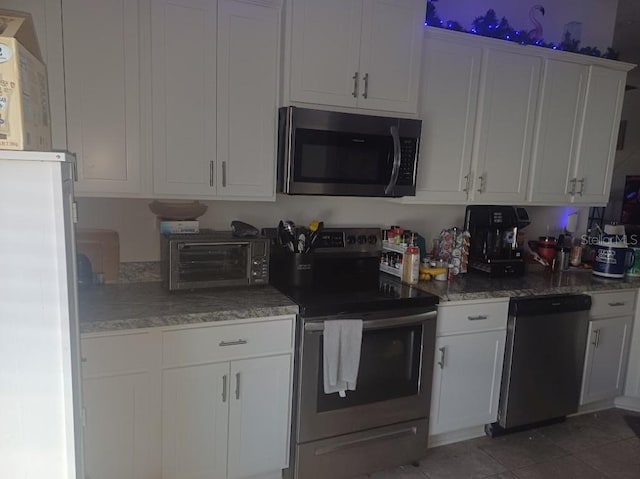 kitchen with stainless steel appliances, white cabinetry, and light tile floors