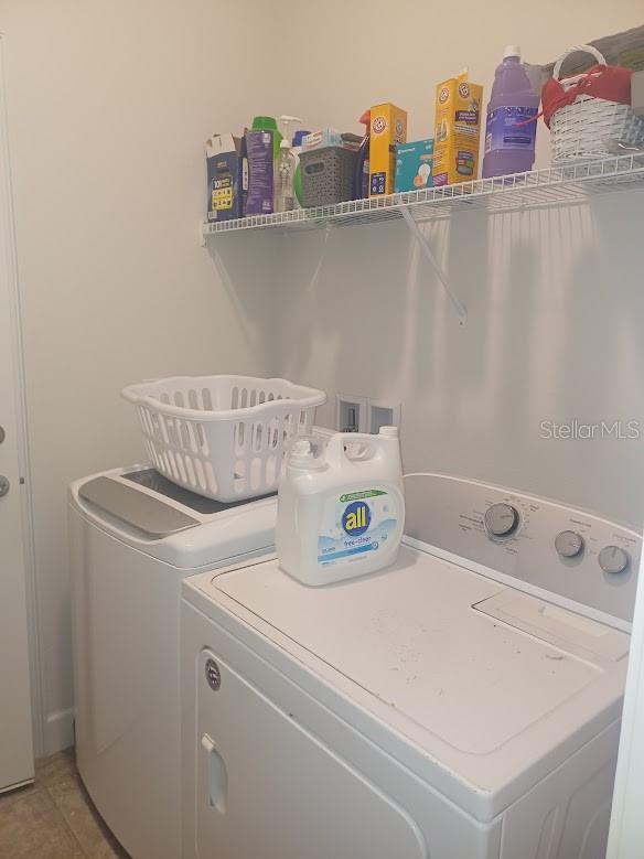 laundry area with independent washer and dryer and light tile floors