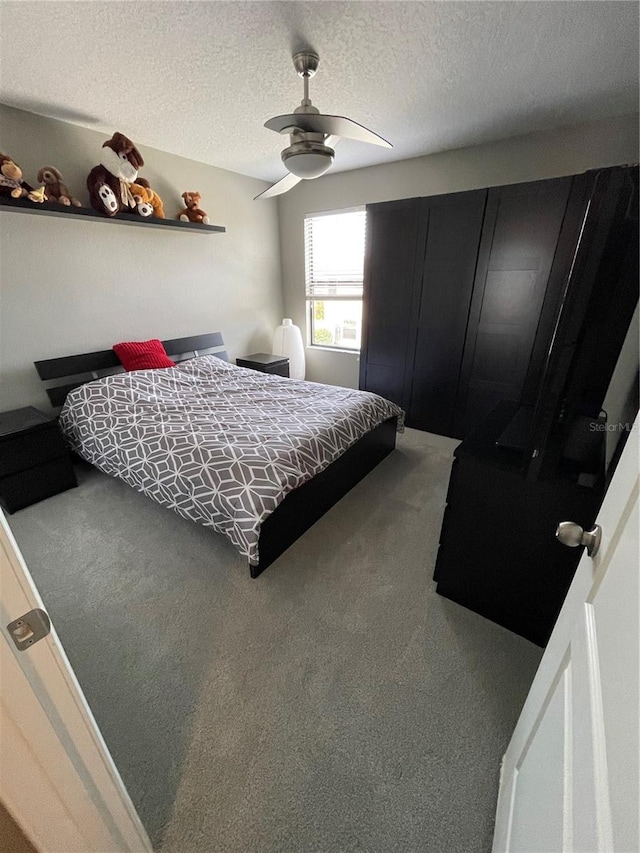 carpeted bedroom featuring ceiling fan and a textured ceiling