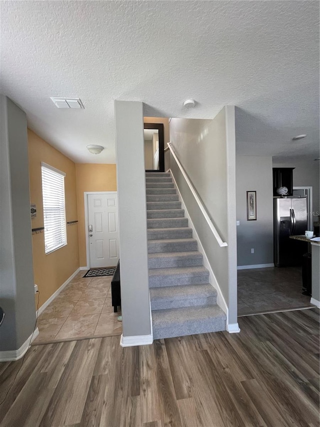 stairway with a textured ceiling and dark wood-type flooring