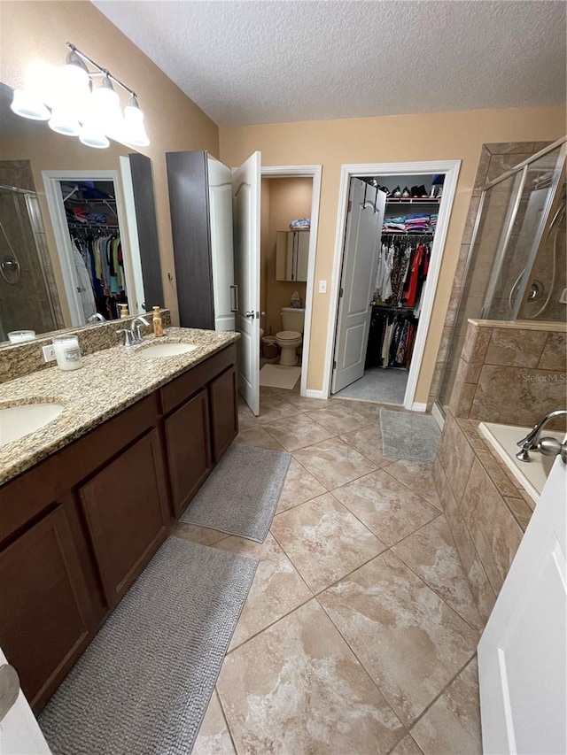 full bathroom featuring tile flooring, a textured ceiling, toilet, separate shower and tub, and double vanity