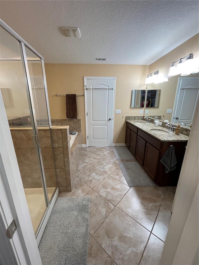 bathroom featuring a textured ceiling, plus walk in shower, double sink vanity, and tile flooring