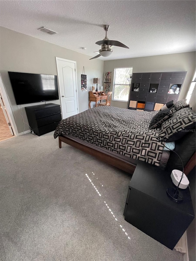 carpeted bedroom featuring ceiling fan and a textured ceiling