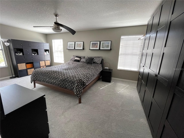 carpeted bedroom featuring a closet, a textured ceiling, multiple windows, and ceiling fan