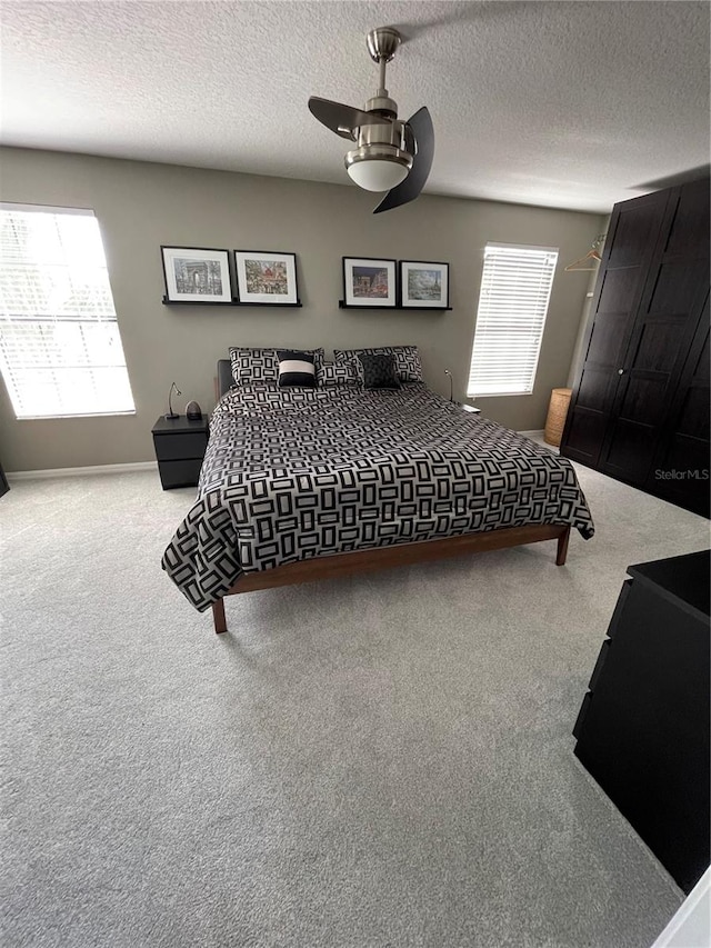 bedroom featuring light carpet, a textured ceiling, and ceiling fan