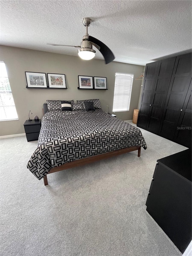 bedroom featuring light colored carpet, ceiling fan, and multiple windows