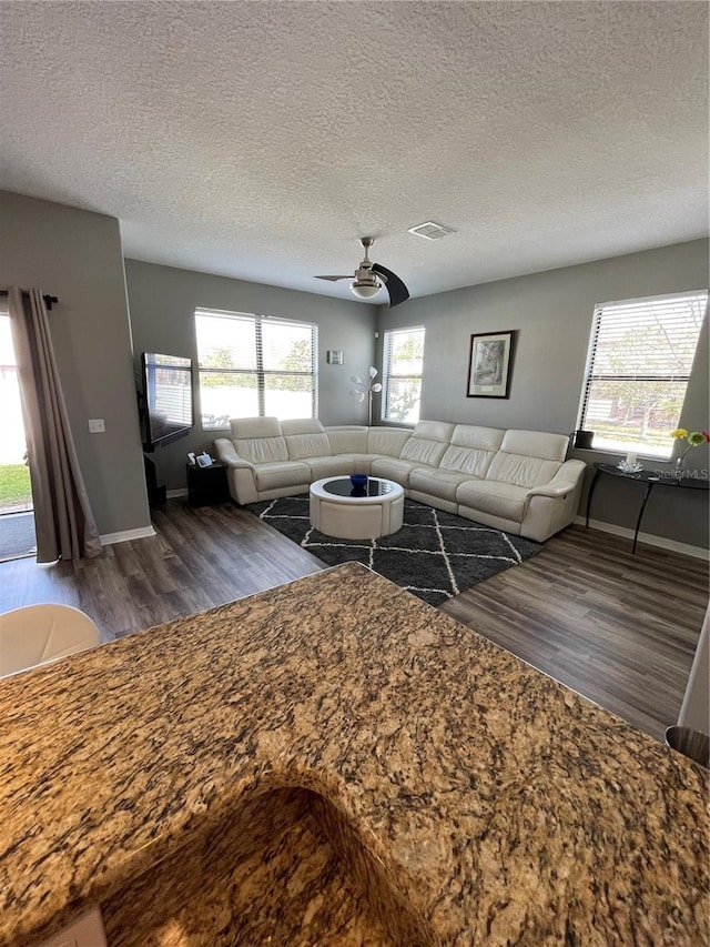 unfurnished living room featuring a textured ceiling, dark hardwood / wood-style floors, and ceiling fan