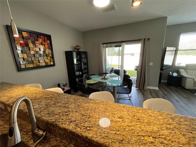 dining area featuring dark hardwood / wood-style floors, a textured ceiling, and a healthy amount of sunlight