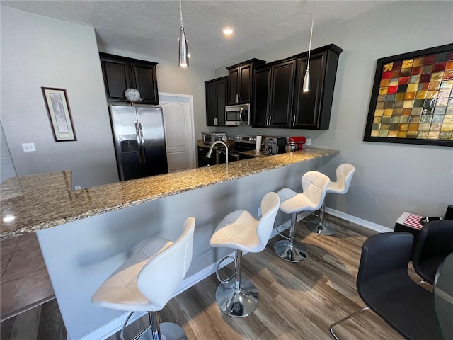 kitchen featuring appliances with stainless steel finishes, kitchen peninsula, dark hardwood / wood-style floors, and a breakfast bar