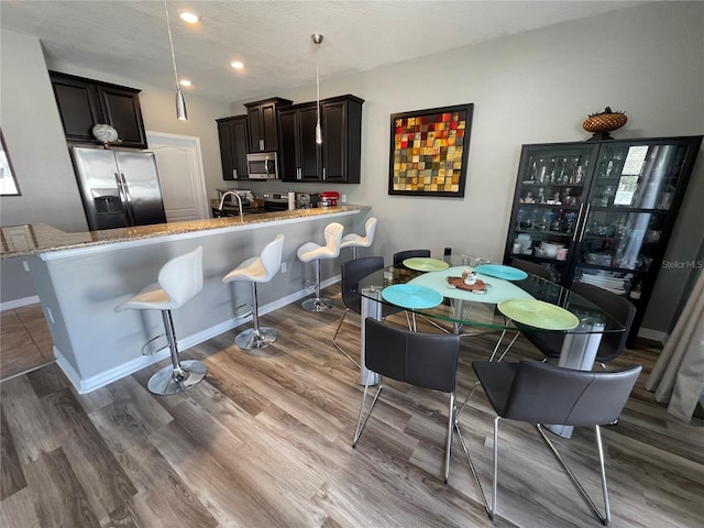 kitchen featuring light stone countertops, a kitchen breakfast bar, stainless steel appliances, and hardwood / wood-style flooring