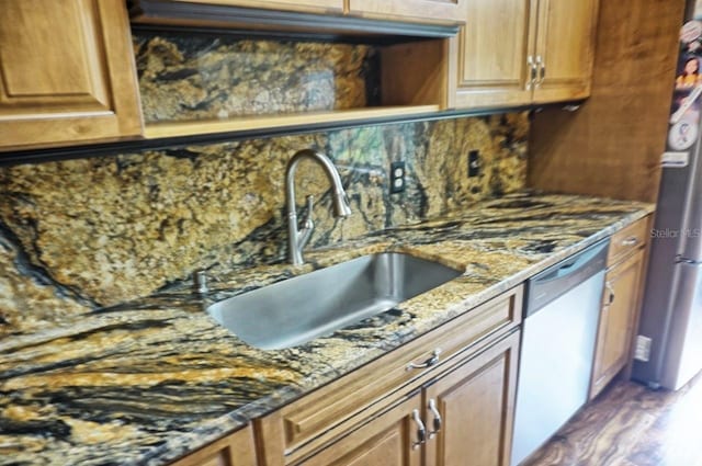 kitchen featuring tasteful backsplash, stone counters, stainless steel dishwasher, hardwood / wood-style floors, and sink