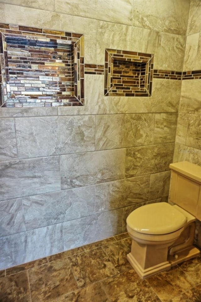 bathroom with tile walls and toilet