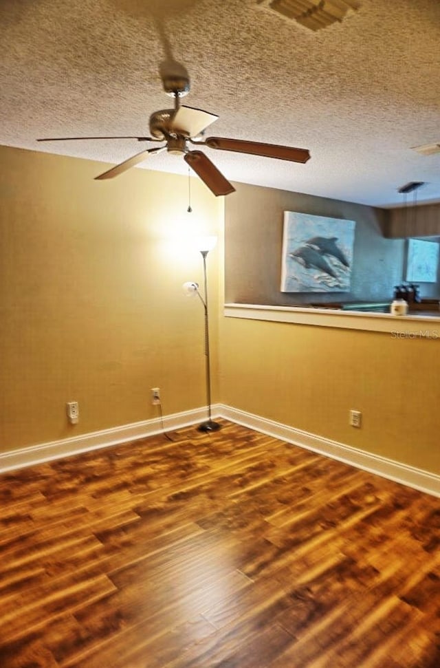 empty room with ceiling fan, hardwood / wood-style floors, and a textured ceiling