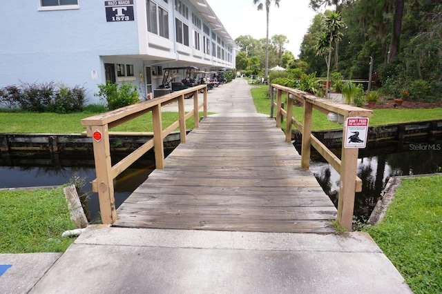 view of dock featuring a lawn and a water view