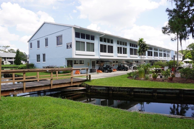 view of dock with central AC unit, a lawn, and a water view