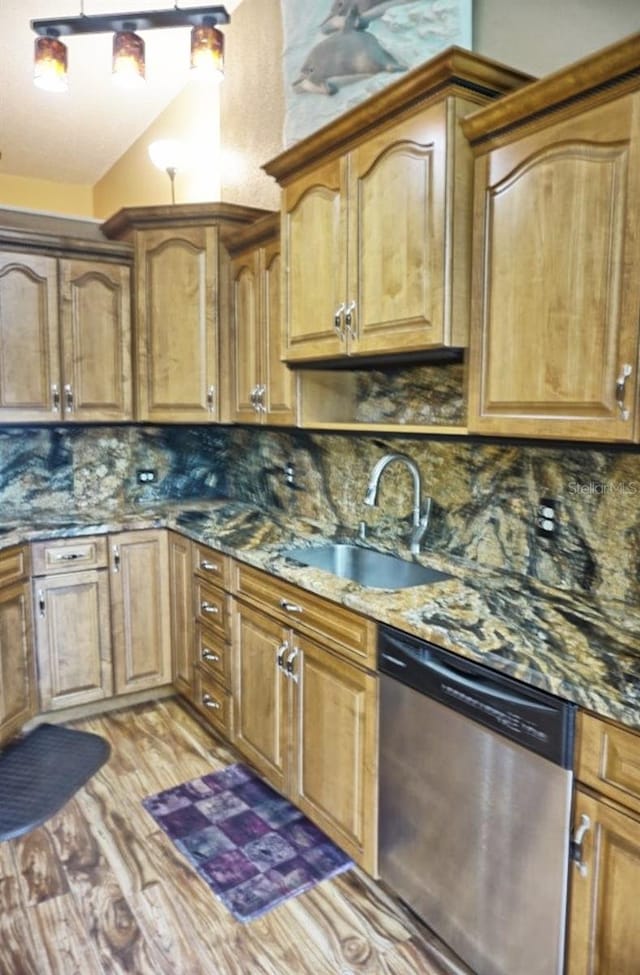 kitchen with dishwasher, sink, light hardwood / wood-style flooring, backsplash, and dark stone countertops