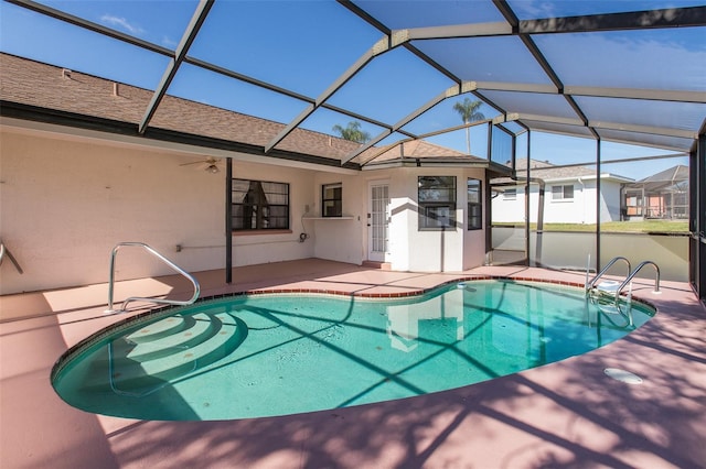 view of swimming pool with glass enclosure, ceiling fan, and a patio