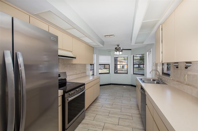 kitchen with ceiling fan, cream cabinets, appliances with stainless steel finishes, backsplash, and sink