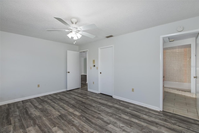 interior space with a textured ceiling, dark hardwood / wood-style floors, ceiling fan, and ensuite bathroom