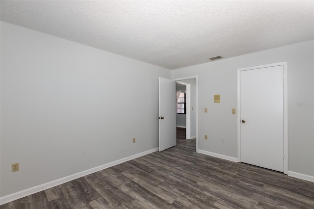 unfurnished bedroom featuring a textured ceiling and dark hardwood / wood-style flooring