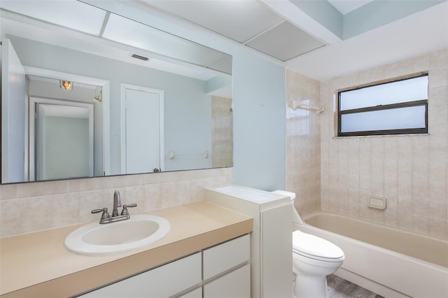 full bathroom with tiled shower / bath combo, vanity, backsplash, and toilet